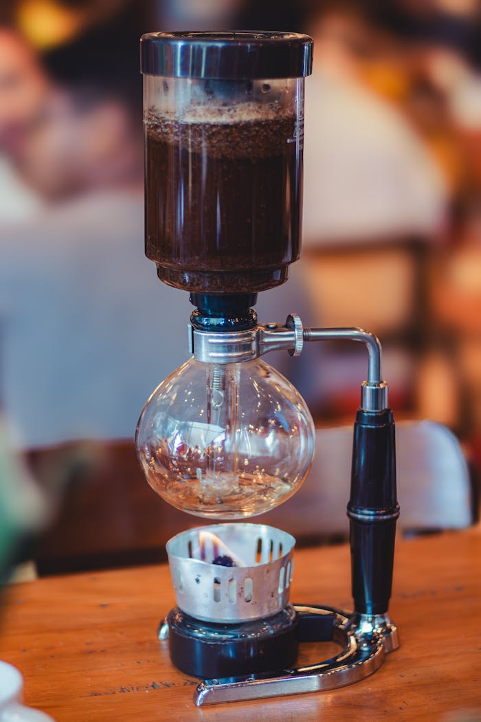 High-quality shot of a sleek siphon coffee maker on a wooden table indoors.
