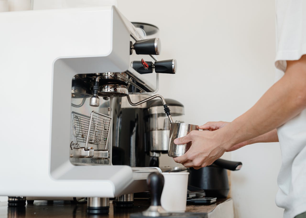 Close-up of a barista's hands using a coffee machine to make espresso indoors.